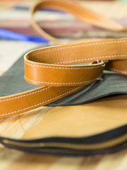 Tan leather fanny pack with double zipper closure and adjustable strap. The Lore by deux mains. Detailed shot of contrast white stitching on strap. 