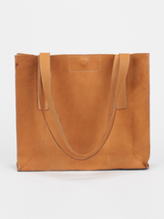 Tan leather Classic City Tote with inner tube bottom panel, and magnetic closure by deux mains. Front view with handles folded over. 