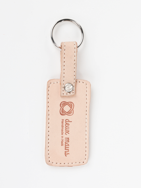 Genuine natural leather keychain. Rectangular with deux mains logo and “Handmade in Haiti” tagline. Front view. 
