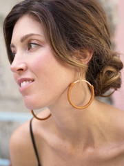 Tan leather Hispaniola Hoop Earrings with individually crafted wooden circle centerpiece. Close up of female model wearing earrings.