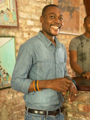  Tan Leather and Tire Cuff featuring upcycled inner tube and snap closure. Shot of male model wearing Leather and Tire Cuff and laughing. 