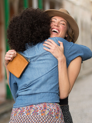 Inner tube and tan leather Maudernise Pouch with zipper closure, by deux mains. Shot of two female models hugging and laughing. 