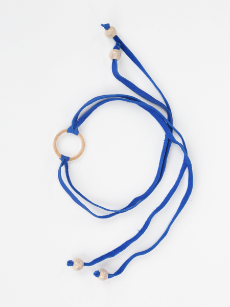 Royal blue leather Bonjou Wrap Bracelet with wooden ring center, and cream ceramic beads. Top view arranged in a loop. 